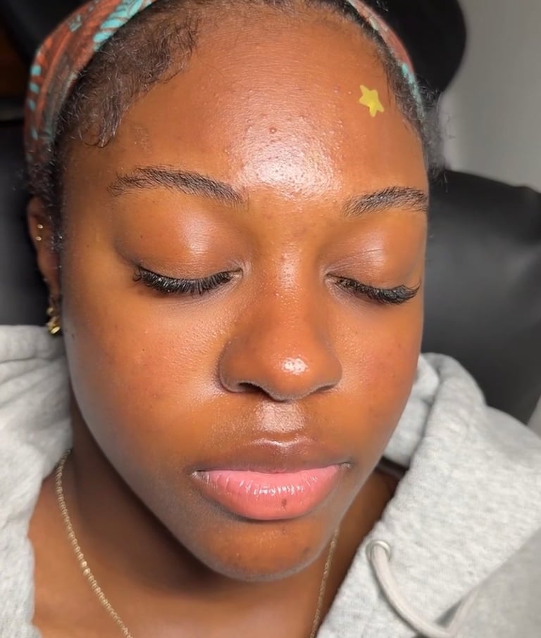 Woman with closed eyes wearing a colorful headwrap and gold forehead sticker, showcasing natural skin and makeup